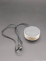 Amazon Echo Dot with attached cable on black background