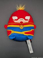 Front view of Captain Marvel plush showing embroidered face, costume and tuft of hair