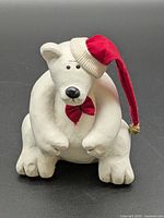 Front view of white wood polar bear wearing red hat and bowtie