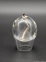 front view of clear glass oil candle showing overall form and wick