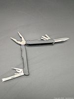 Multitool fully opened showing pliers, knife blade, file/serrated tool, screwdrivers