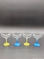 Front view of four coupe glasses showing alternating blue and yellow frosted stems