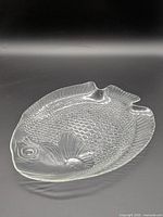 Top view of clear pressed glass fish-shaped plate showing overall form and scale texture