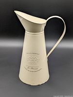 Front view showing crown graphic and French text on tall white metal pitcher