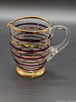 Front view showing horizontal purple and gold stripes, gold rim and foot