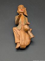Full view of carved wooden seated female drummer