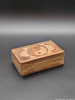 Three-quarter view of box showing carved lid and wood grain