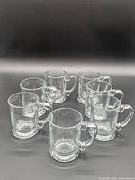 Seven clear glass mugs arranged upright showing overall quantity and style