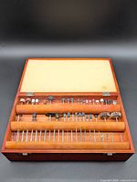 Open wooden case showing all rotary tool accessories