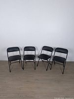 Four black folding chairs standing open on floor