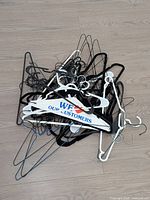 Pile of assorted plastic and metal hangers on wood floor
