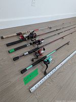 Six fishing rods with reels laid out next to tape measure