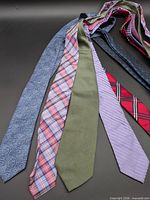 Group of seven neckties laid out to show full length and patterns