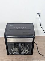 Front view of shredder plugged in showing bin with shredded paper