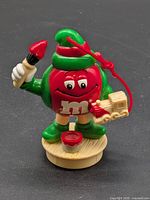 Front view of ornament showing character, paintbrush, toy train, base