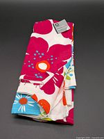 Folded stack of three floral kitchen towels with tag visible