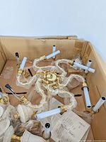 Chandelier components in box showing eight arms, candle sleeves, and hardware