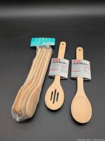 Full lot showing two OXO spoons with labels and sealed six-piece wooden utensil set