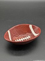 Top angled view of brown football-shaped ceramic bowl with white laces