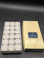 Closed box beside tray showing 18 white candles