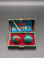 Pair of Baoding balls in opened brocade box, interior label visible