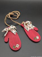 Pair of red wooden mitten ornaments connected by jute hanger