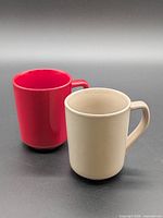 Front view of two ceramic mugs, red and beige