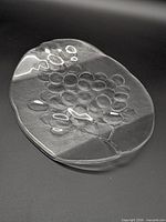 Top view of clear pressed glass tray showing grape cluster relief