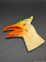 Left side view showing orange beak, cream skin, green accents