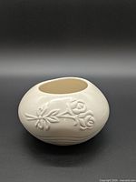 Front view of rounded off-white ceramic vase showing embossed rose motif