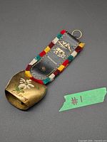 Front view showing brass bell with hand-painted edelweiss and "Lucerne" text, leather strap with multicolour fringe and printed motifs