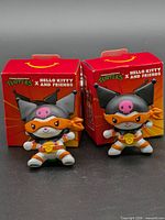 Two figurines in front of their boxes
