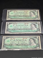 Front view of all three 1967 Canadian $1 notes in sleeves