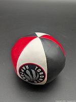 Full view of soft toy ball showing red, white, black panels and Raptors logo