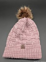 Full view of pink knit beanie showing pom and cuff