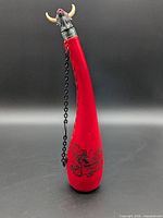 Full view of red leather wineskin showing shape, chain and stopper