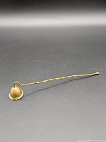 Full view of brass candle snuffer showing overall form