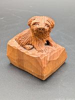 Front view of carved wooden dog on block base
