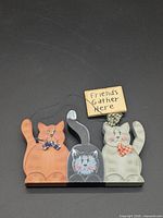 Front view of painted wooden cat sign and attached plaque