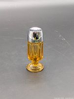 Full view of amber glass footed shaker with metal lid