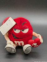 Front view of red M&M plush holding heart