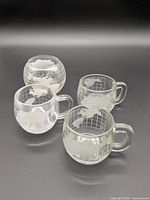 Front view of all four globe glass mugs showing world map design