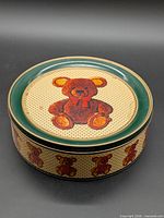 Isometric view of round tin showing lid and side teddy bear design
