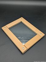 Front angled view of wooden picture frame showing glass and screw details