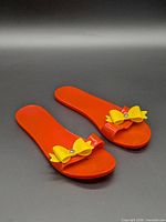 Top view of orange plastic sandals with yellow bows