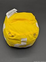 Top view of yellow plush cube showing fabric and question mark patches