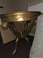 Side view of round gilt wood table showing carved apron and leg detail