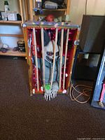 Front view of boxed cage displaying monster figure behind bamboo bars, purple string lights, plastic hand extending, visible power cord