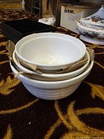 Three nested cream ceramic mixing bowls with cardboard spacers