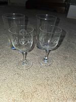 Two cylindrical water glasses and two stemmed cordial glasses showing size difference and etched pattern